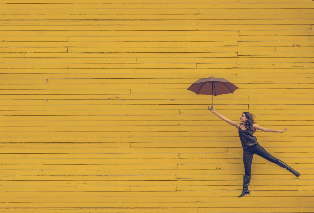 Person with umbrella against yellow wall
