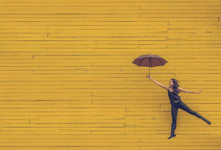 Person with umbrella against yellow wall